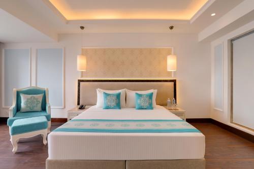 a bedroom with a large bed and a blue chair at Lemon Tree Premier Budhanilkantha Kathmandu, Nepal in Kathmandu