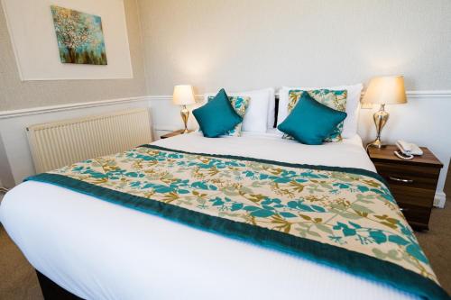 a bedroom with a large bed with blue pillows at Raven Hall Hotel in Ravenscar