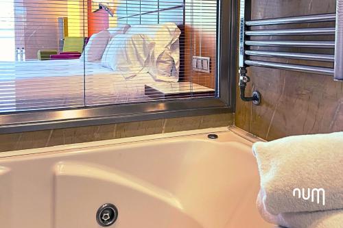 a bath tub in a bathroom with a window at Num Hotel in Salou