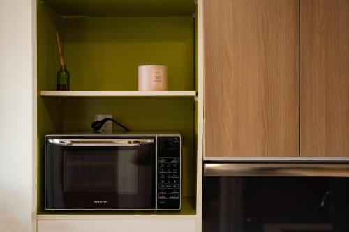 a kitchen with a microwave and a shelf at APARTMENT AIRPORT TAN SON NHAT - free Pool & Gym in Ho Chi Minh City