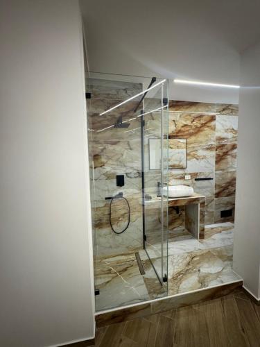 a glass shower in a room with a stone wall at Sistra 12 in Catania