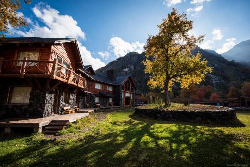 una casa en un campo con un árbol al lado en Rocanegra Mountain Lodge en Las Trancas
