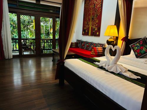 zwei Betten in einem Zimmer mit zwei Schwänen darauf in der Unterkunft Hongkhao Village in Chiang Mai