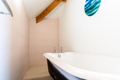 uma casa de banho com uma banheira branca e uma janela em West Town Barn em Exeter