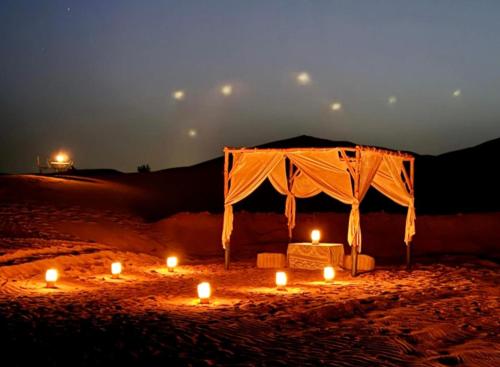a tent with candles in the sand at night at Luxury Bedouin Camp in Merzouga