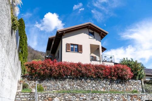 a house on a stone wall with red bushes at Casa Vista Lago in Sorico