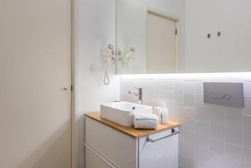 a white bathroom with a sink and a mirror at GuestReady - Cedofeita Pool Suite 3 in Porto