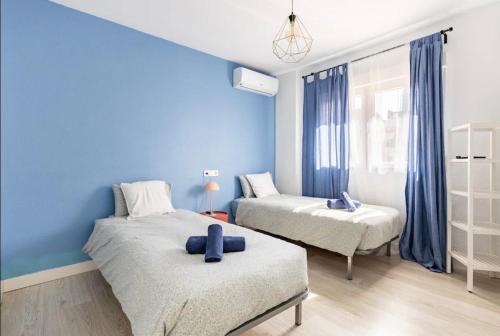 a bedroom with two beds and a blue wall at Apartamentos Duque Cartagena in Cartagena