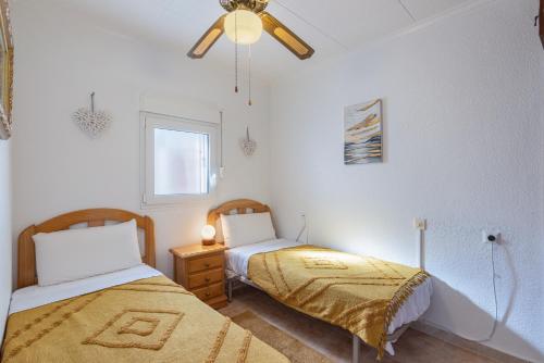 a bedroom with two beds and a ceiling fan at Casa Goleta in Torrevieja