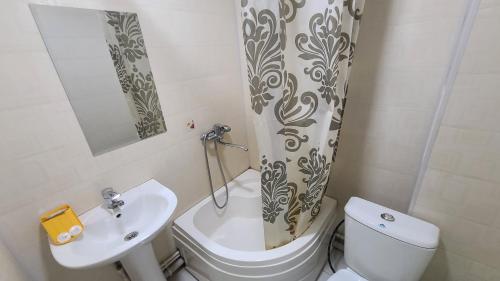 ein Badezimmer mit einem WC, einem Waschbecken und einem Duschvorhang in der Unterkunft FAYZ HOTEL in Karmana