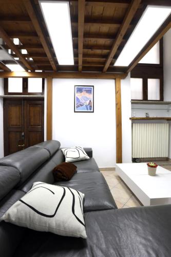 a living room with a black leather couch with pillows at Loft Piazza Cavour Vercelli in Vercelli
