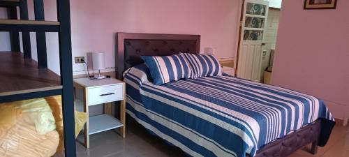 a bedroom with a bed with a striped comforter and a side table at La Casita II in Cochabamba