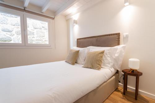 1 dormitorio con 1 cama con sábanas blancas y ventana en Alojamento Porta14.3, en Chaves