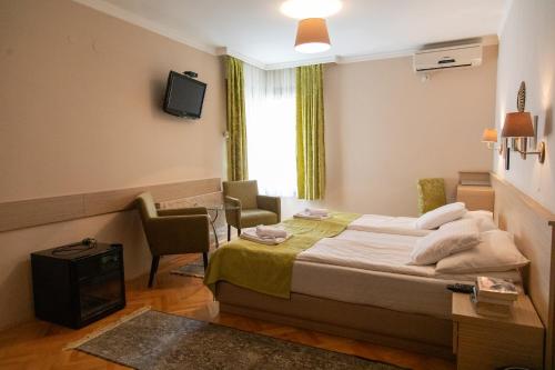 a hotel room with a bed and a table and chairs at Cvetni Konaci in Vrnjačka Banja