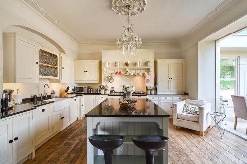 a kitchen with white cabinets and a chandelier at Berkeley House near Bath in Bath