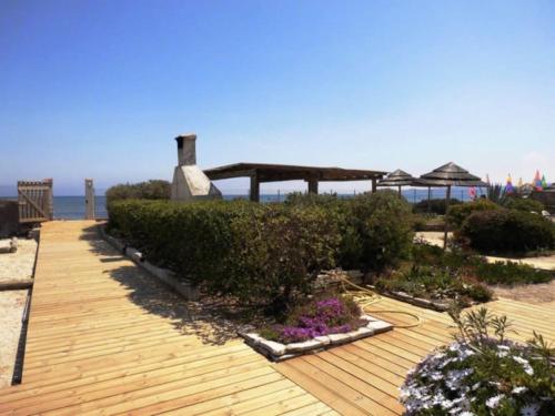 Una terraza de madera con arbustos y flores en la playa. en Appartement 4 personnes au calme, en Hyères
