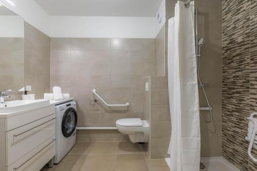 une salle de bain avec toilettes et lavabo et une machine à laver dans l'établissement OVELIA Saint-Etienne - Les Arches de la Montat, à Saint-Étienne