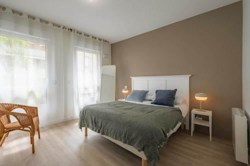 une chambre avec un lit, une chaise et une fenêtre dans l'établissement OVELIA Saint-Etienne - Les Arches de la Montat, à Saint-Étienne