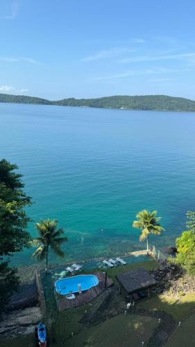 a view of a large body of water with palm trees at Ocean Green Flats in Angra dos Reis