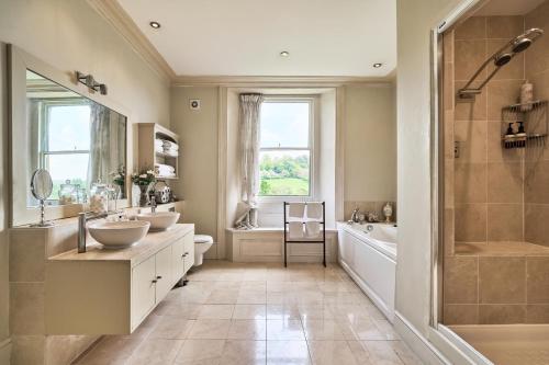 uma casa de banho com 2 lavatórios, uma banheira e um chuveiro em Berkeley House near Bath em Bath