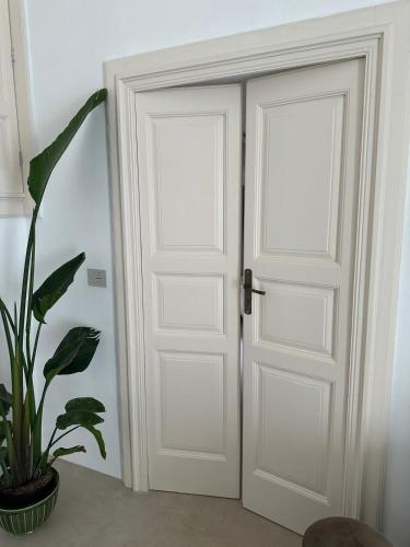 two white doors in a room with a plant at Suite Sami Charming Home in Ostuni