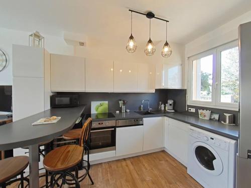 une cuisine avec des armoires blanches et une table et des chaises dans l'établissement Vos vacances les pieds dans le sable., à Saint Pierre La Mer