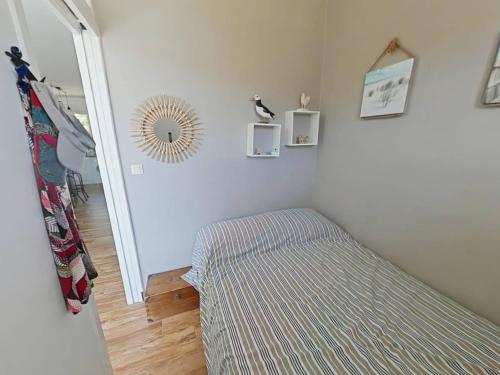 Cette chambre comprend un lit et un miroir mural. dans l'établissement Vos vacances les pieds dans le sable., à Saint Pierre La Mer