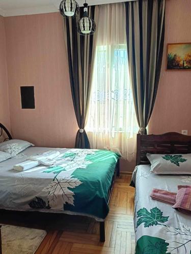 a bedroom with two beds and a window with curtains at Avtos's Winery in Tbilisi City