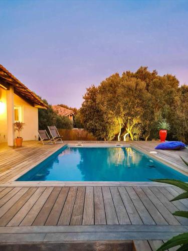 une piscine avec une terrasse en bois à côté d'une maison dans l'établissement La Casa Soliam, à Bonifacio