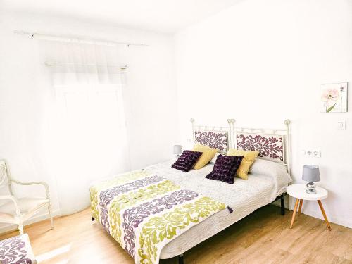 a white bedroom with a bed and a chair at Casa del Arquillo in Teruel