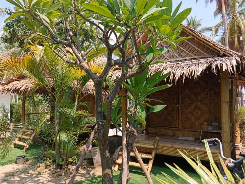 a house with a thatched roof with a bench in front at Bamboo homestay at samroiyot in Baanphakrimlay 
