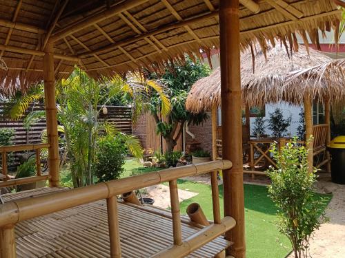 a patio with a straw umbrella and a deck at Bamboo homestay at samroiyot in Baanphakrimlay 