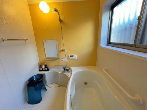 a bathroom with a tub and a sink and a window at Sea Front Villa in Tateyama