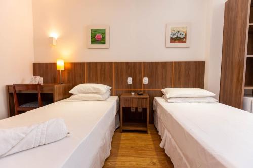 a room with two beds and a desk at Rede Andrade Canada in Rio de Janeiro