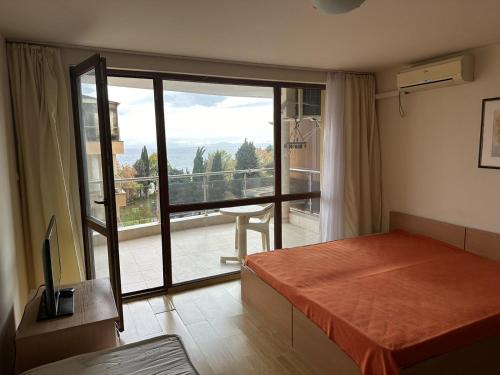 a bedroom with a bed and a balcony with a view at Julia Vigo Panorama apartments in Nesebar