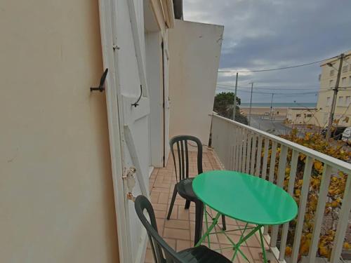 d'un balcon avec une table et des chaises vertes. dans l'établissement Appartement avec balcon proche plage, à Saint Pierre La Mer