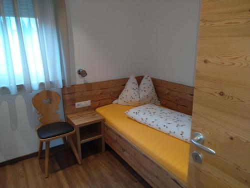 a small bedroom with a yellow bed and a chair at Chalet Schaller in Tesimo