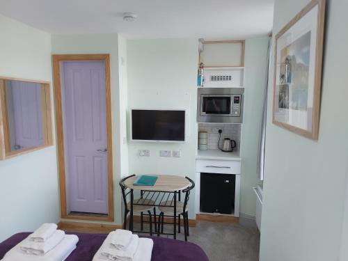 eine kleine Küche mit einem kleinen Tisch und ein kleines Zimmer mit einem Tisch und Stühlen in der Unterkunft Ellerhow in Windermere