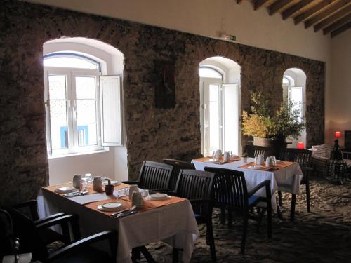 a dining room with tables and chairs and windows at Herdade Do Azinhal in Santa Clara-a-Velha