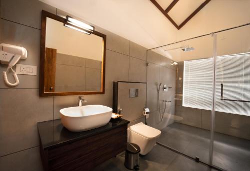 uma casa de banho com um lavatório, um WC e um espelho. em Coffee and Pepper Plantation Homestay em Thekkady