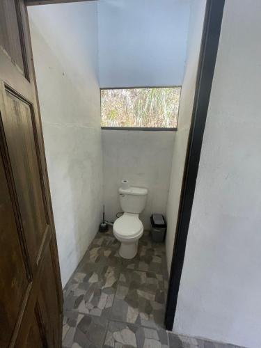 a small bathroom with a toilet with a window at Jungle Container Escape in Golfito