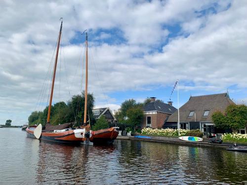 two boats are docked at a dock in the water at PUUR Eastermar - monumentaal, authentiek en luxe koetshuis aan open vaarwater met jacuzzi en sauna in Oostermeer