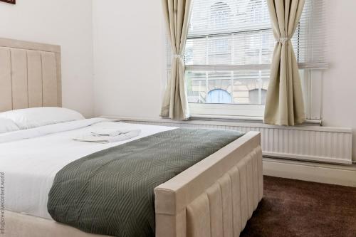 ein Schlafzimmer mit einem großen Bett und einem Fenster in der Unterkunft Hampton Court Cottage in Hampton