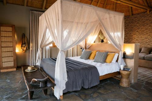 a bedroom with a canopy bed and a couch at Sandfontein Lodge & Nature Reserve in Sandfontein