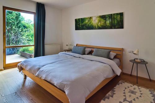 a bedroom with a large bed and a large window at Ferienhaus am Mühlbach Ammersee in Utting am Ammersee