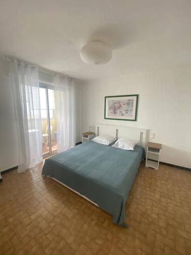 une chambre avec un grand lit et une fenêtre dans l'établissement Jolie appartement à 50m de la plage, à Narbonne-Plage