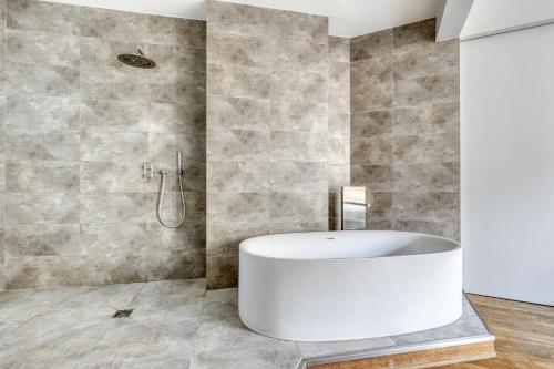 une salle de bain avec une baignoire blanche et une douche dans l'établissement Wonderful & large flat in the 7th - Eiffel Tower, à Paris