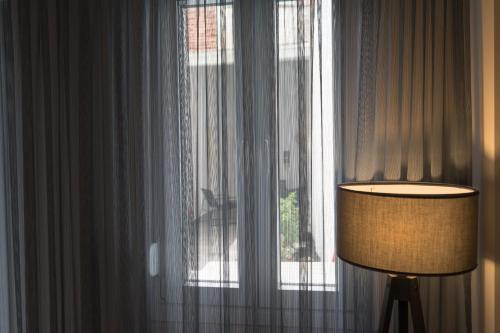 a lamp in front of a window with curtains at Lorien City Center Apartments in Ioannina