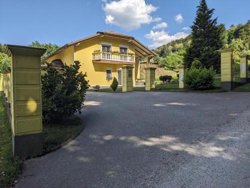 a yellow house with a balcony on a driveway at Apartman Sunny Hills in Krapina