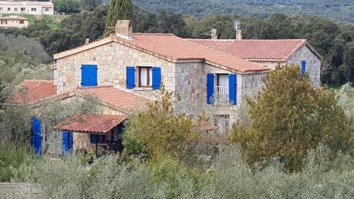 una antigua casa de piedra con persianas azules en Meublés de Tourisme Casa Erbaggio, en Sartène